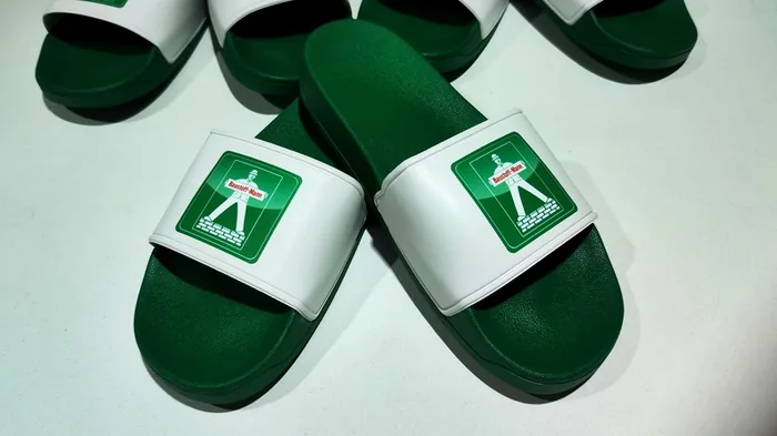 Grüne Badelatschen mit Der-Baustoff-Mann-Logo