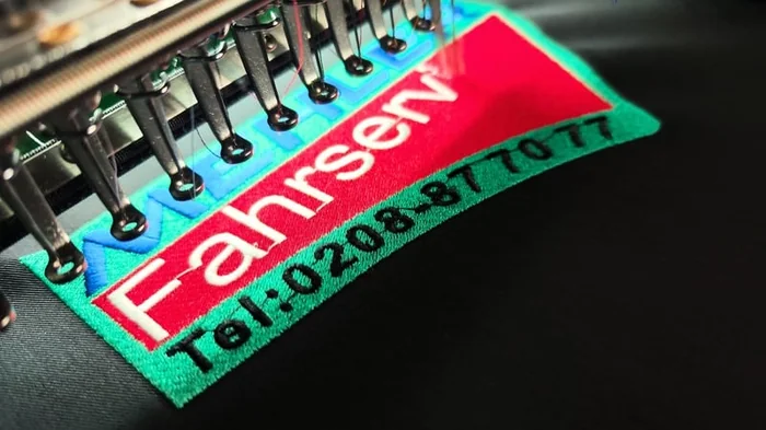 Bestickte Fahrservice-Patch in Rot und Grün, live auf der Stickmaschine